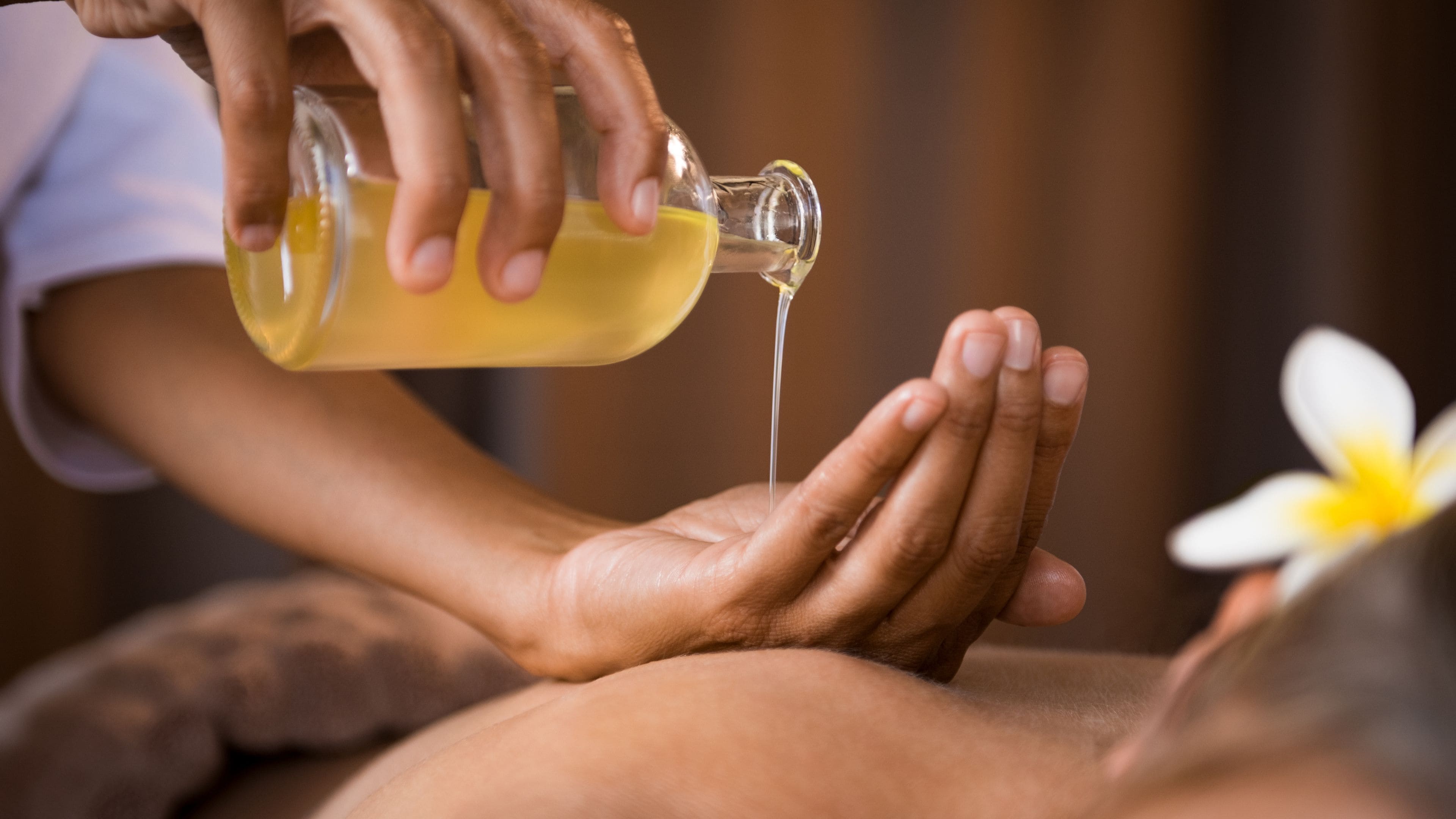 Une personne reçoit un massage, de l’huile étant versée sur ses mains.