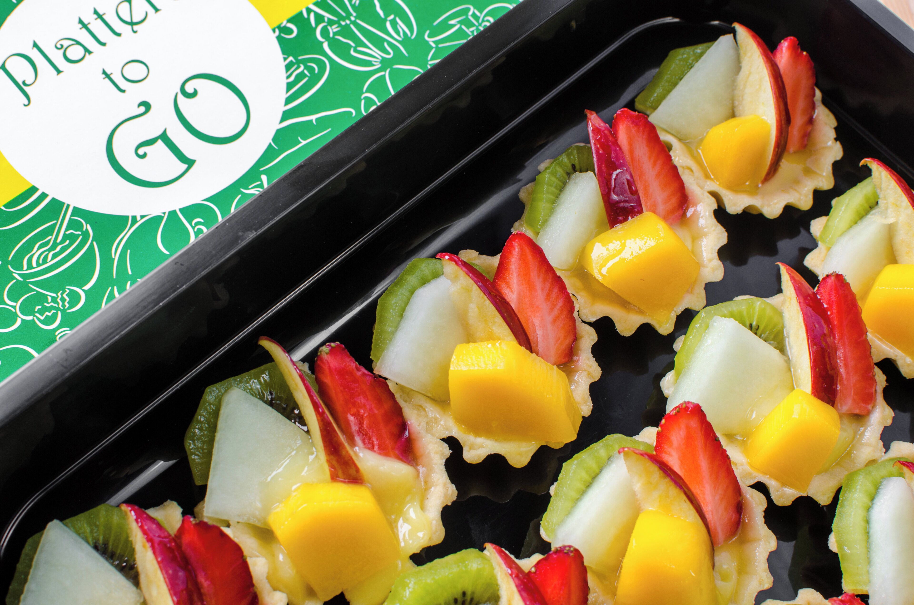 A tray of fruit tartlets with a green and white patterned background.