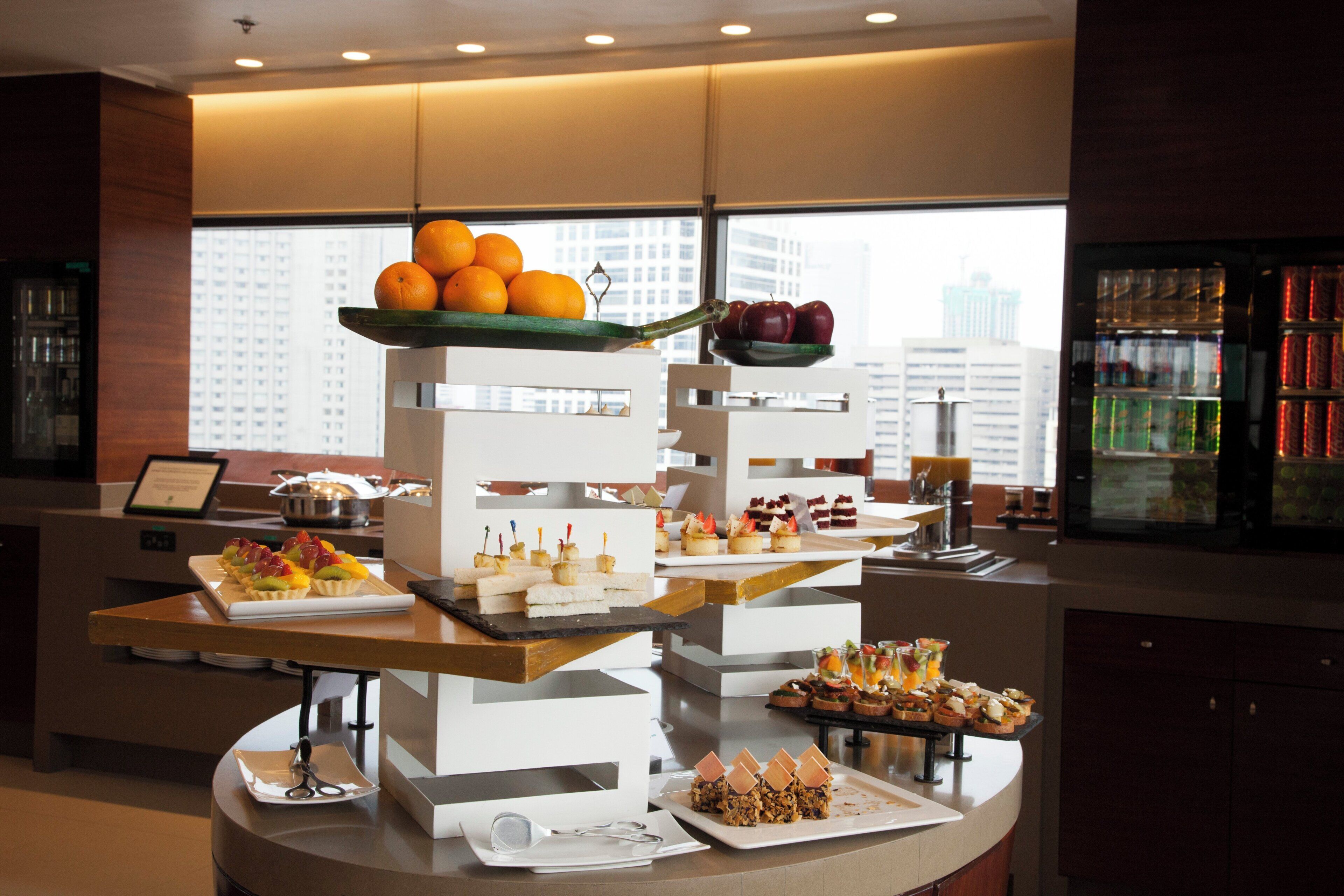 A buffet setup with various food items and a city view in the background.