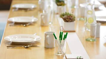 Une table à manger bien dressée, avec des assiettes, des couverts et des verres transparents équipés de pailles.
