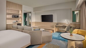 A modern hotel room with a large bed, a sofa, a desk with a chair, a TV, and a small table with a plant. - Holiday Inn & Suites Makati by IHG (Makati)