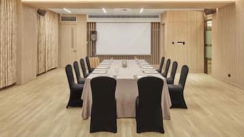 Une salle de conférence avec une longue table, des chaises noires et un écran de projection.