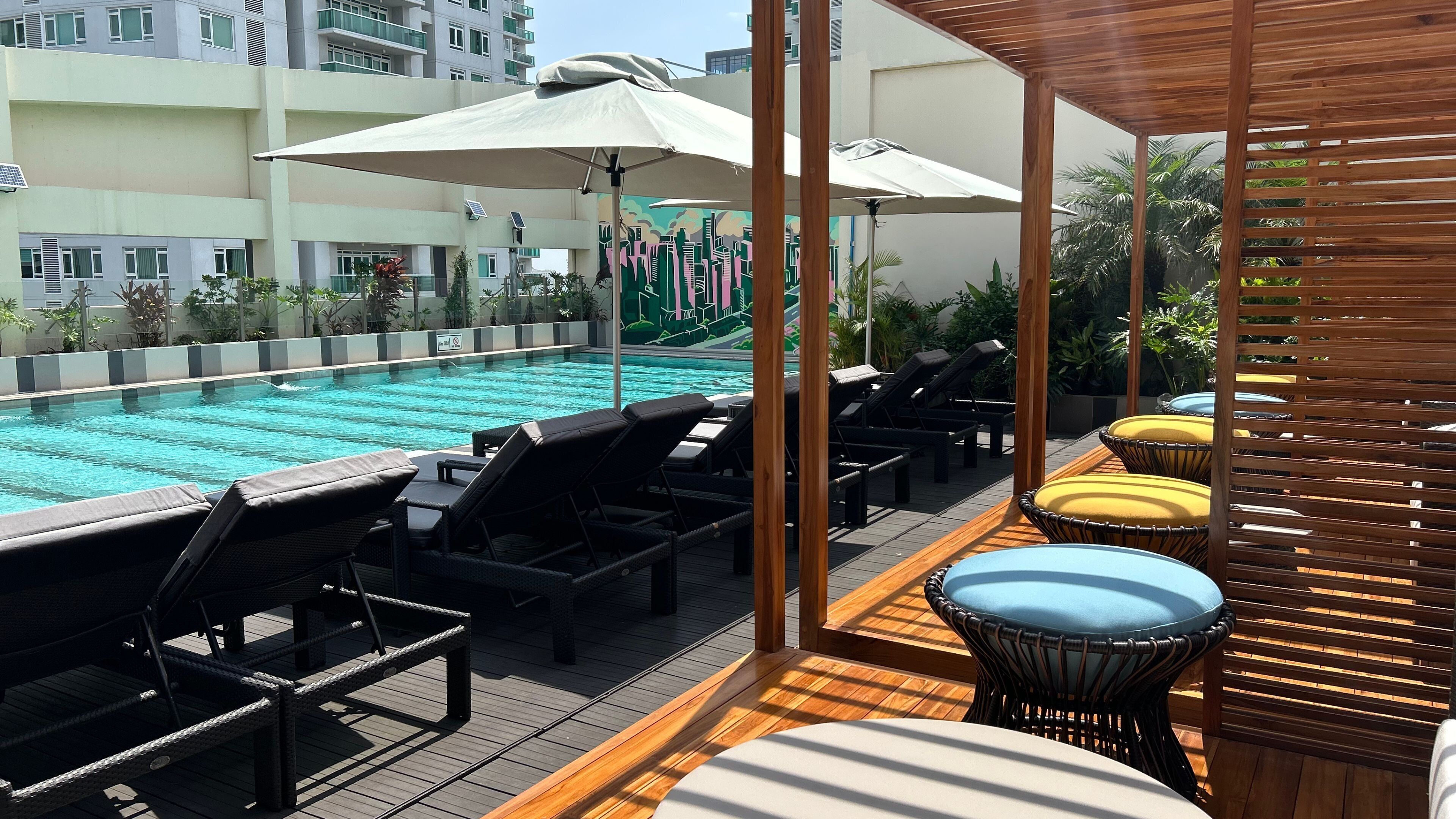 Un área de piscina en la azotea con sillones y sombrillas.