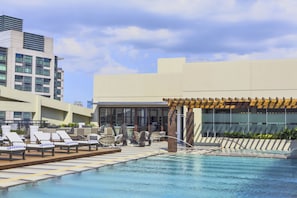 Relax by the rectangular pool surrounded by lounge chairs and a wooden deck.
