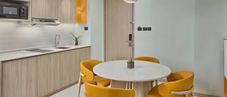 Una cocina moderna con microondas integrado, un fregadero y una mesa redonda de comedor con sillas amarillas.