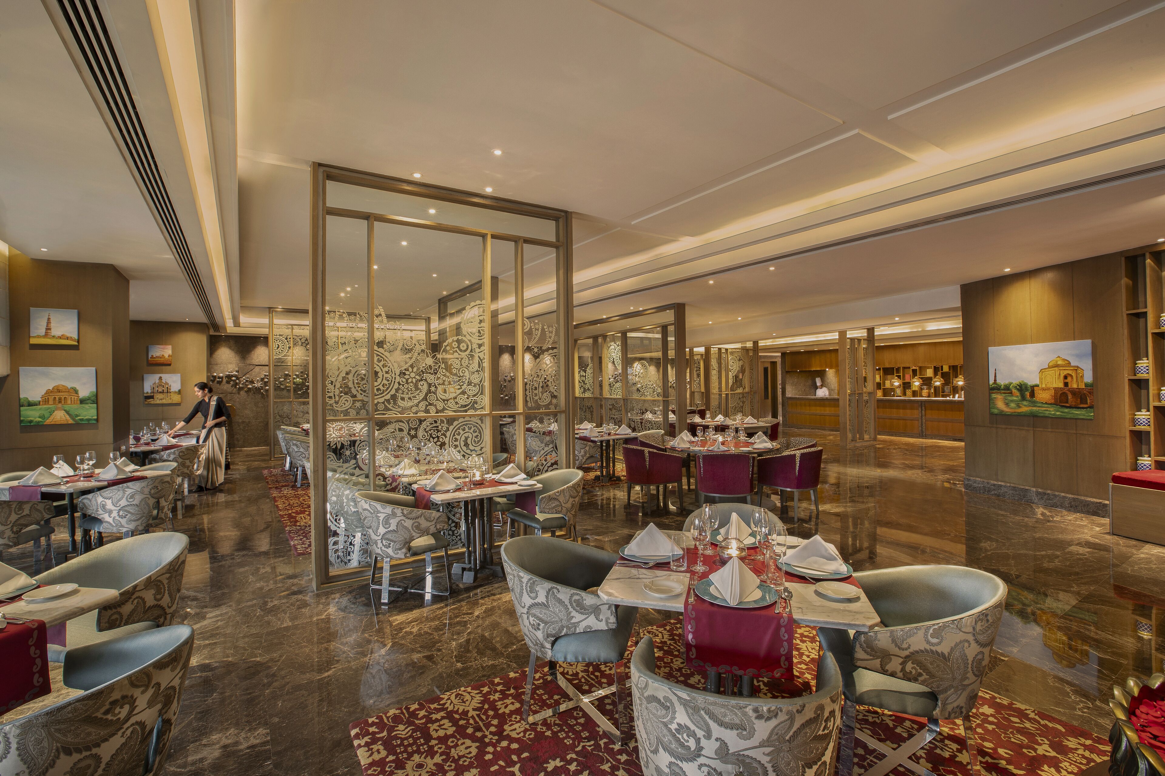 A spacious restaurant with high ceilings, patterned walls, and a variety of seating arrangements including tables and chairs.