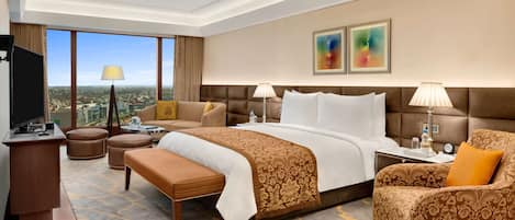 A hotel room with a large bed, a sofa, a desk, and a view of the city.