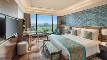 Een moderne hotelkamer met een groot bed, een flatscreen-tv, een bureau met een stoel en uitzicht op de stad.