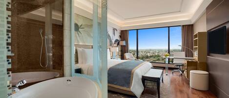 A modern hotel room with a large bathtub, a bed with a view, a desk, and a television.
