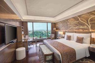 Una camera d'albergo moderna con un letto grande, una TV a schermo piatto, una scrivania con una sedia e vista sulla città.