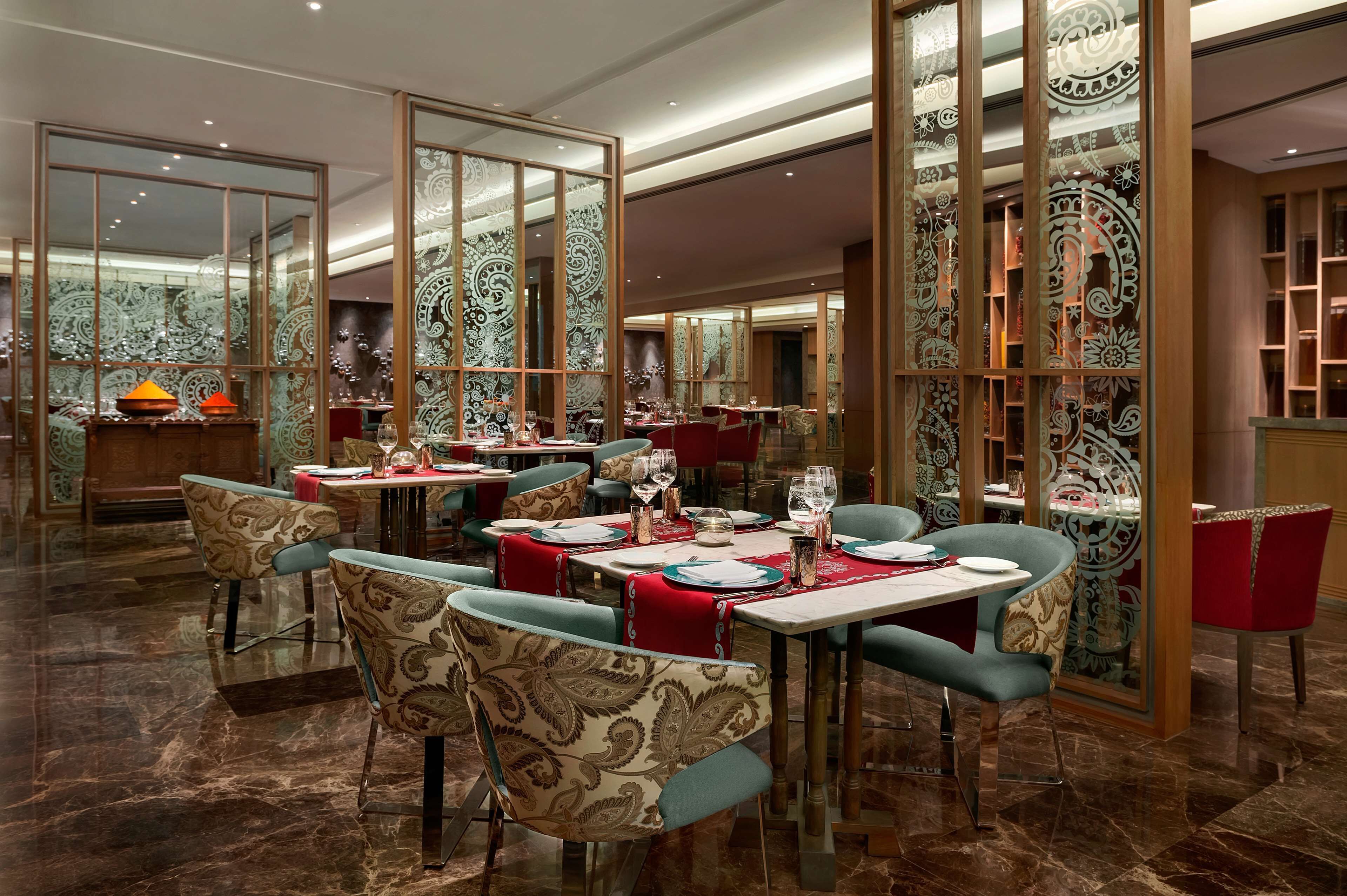 A dining area with tables set for service, chairs with patterned upholstery, and decorative wall panels.