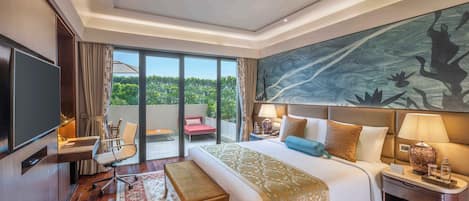 A spacious hotel room with a large bed, a desk, a chair, a TV, and a balcony with a view of greenery.