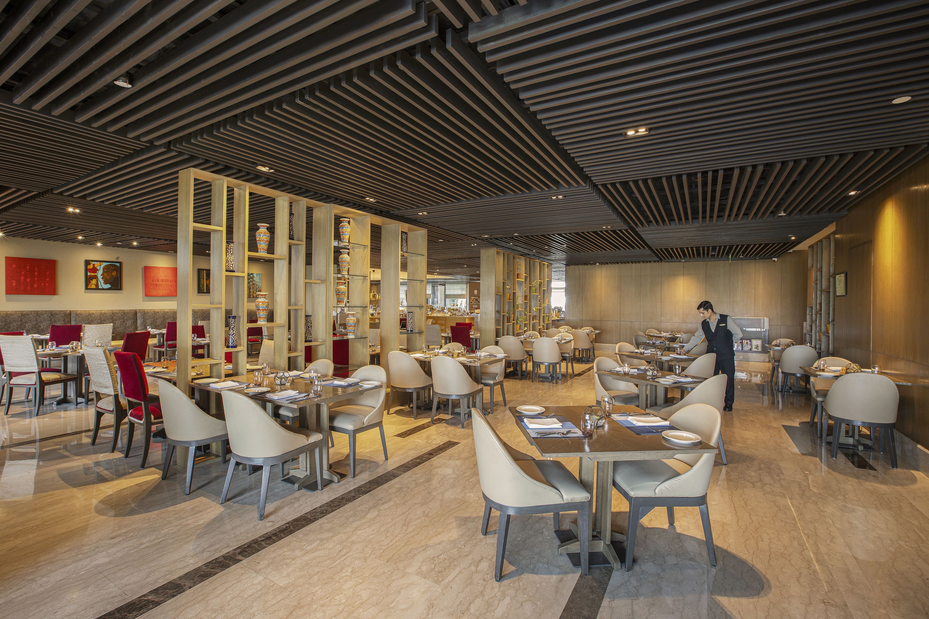Een ruim restaurant met modern decor, met hoge plafonds, marmeren vloeren en diverse zithoeken.
