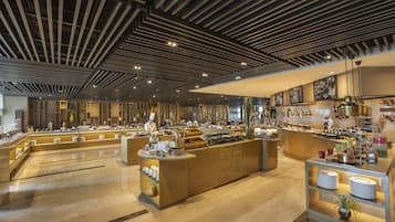 A modern breakfast buffet with a chef preparing food, a variety of food stations, and a clean, well-lit interior.