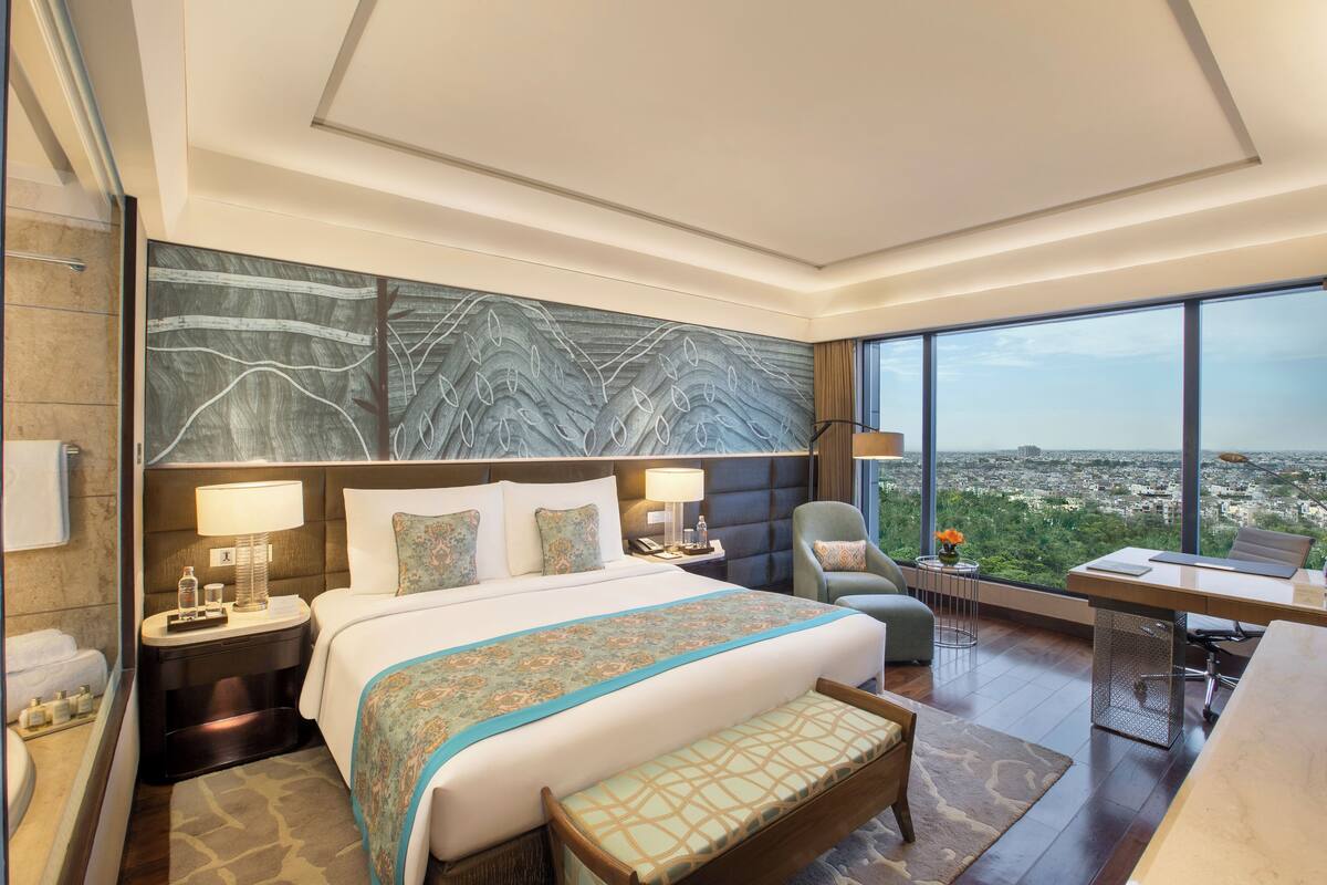 Une chambre d’hôtel moderne, dotée d’un grand lit, d’un bureau et offrant une vue sur la ville.