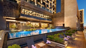 A rooftop pool with lounge chairs and a view of a modern building.
