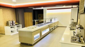 A buffet setup with multiple serving stations, a coffee machine, and a beverage dispenser. - Hotel Susuqui (Sanxenxo)