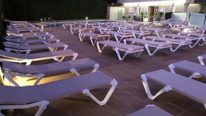 A poolside area with rows of white sun loungers and a tiled floor. - Hotel Susuqui (Sanxenxo)
