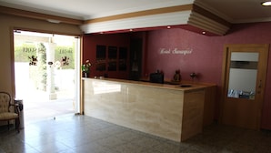 A hotel reception area with a marble counter, a reception desk, a chair, and a door. - Hotel Susuqui (Sanxenxo)