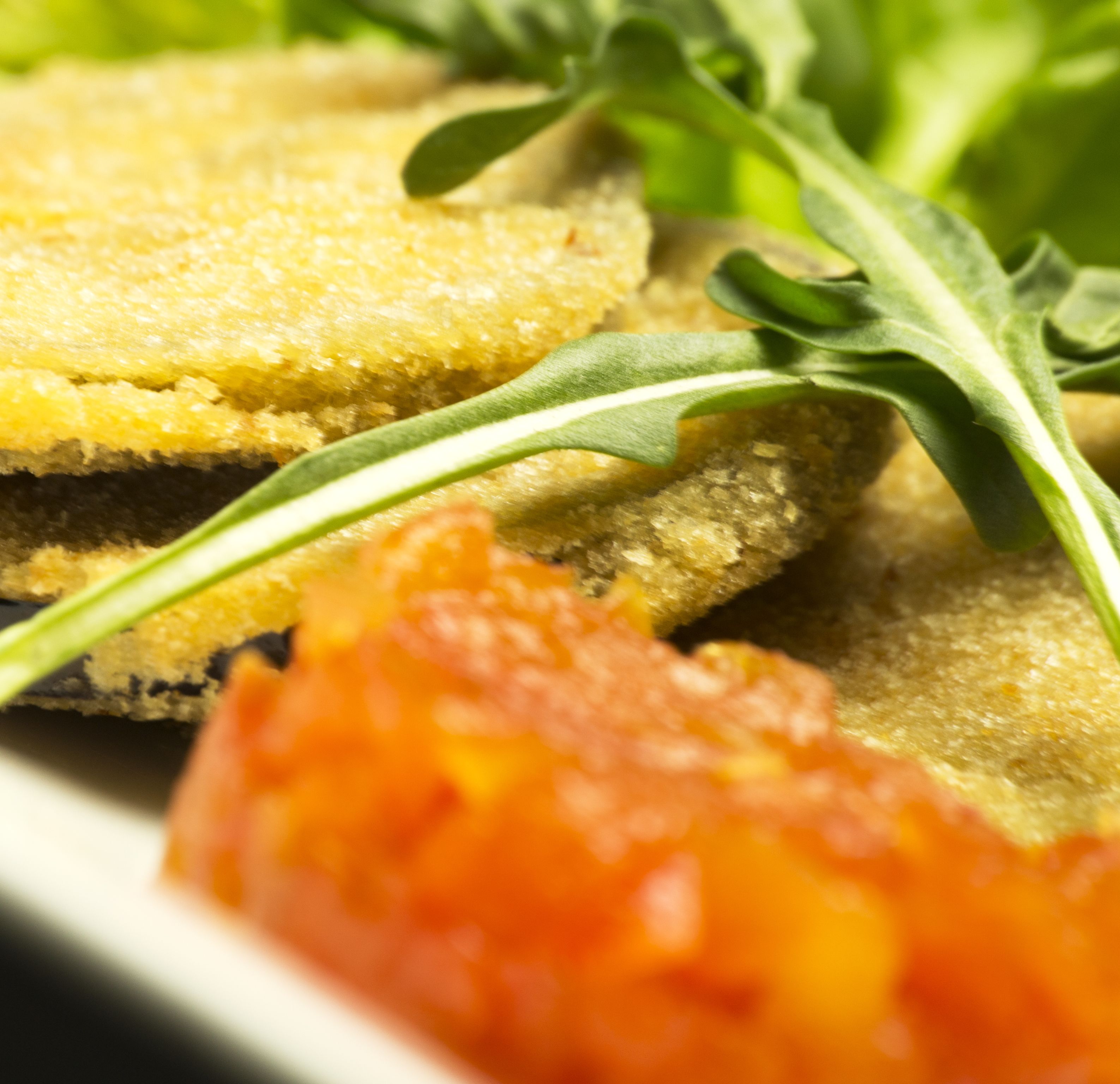 Een bord eten met gepaneerde snacks en rode saus erbij.