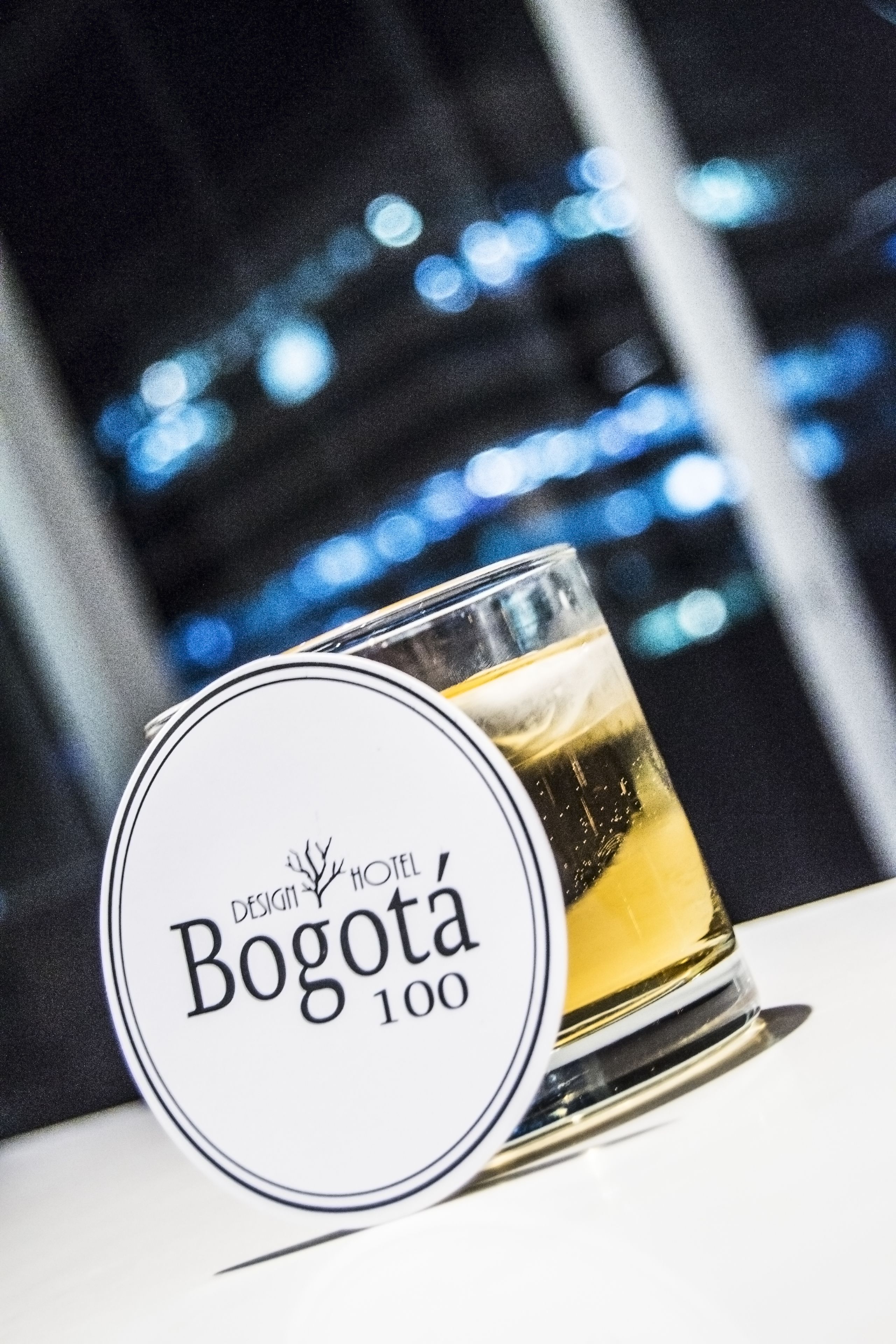 A glass of beer on a table with a circular sign that reads "Bogota 100".