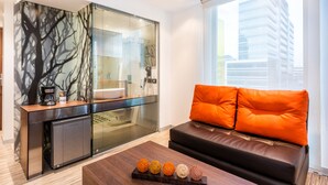 Un espacio moderno con zona de estar, sofá, cafetera y una bandeja decorativa con esferas.