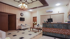 Um saguão de hotel com balcão de recepção, área de estar e um candelabro.
