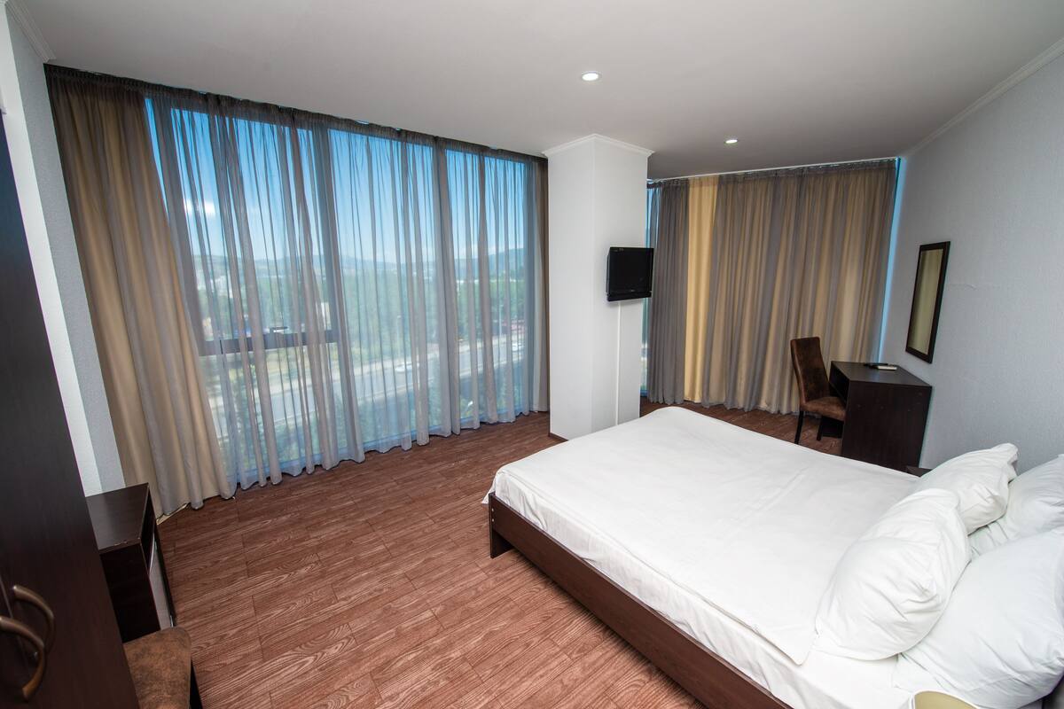 Una habitación de hotel con una cama grande, una silla, un escritorio y un televisor.