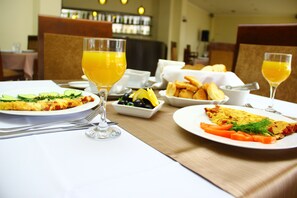 A breakfast setting with plates of food, glasses of orange juice, and a variety of side dishes. - Hotel Shine Palace (Tbilisi)