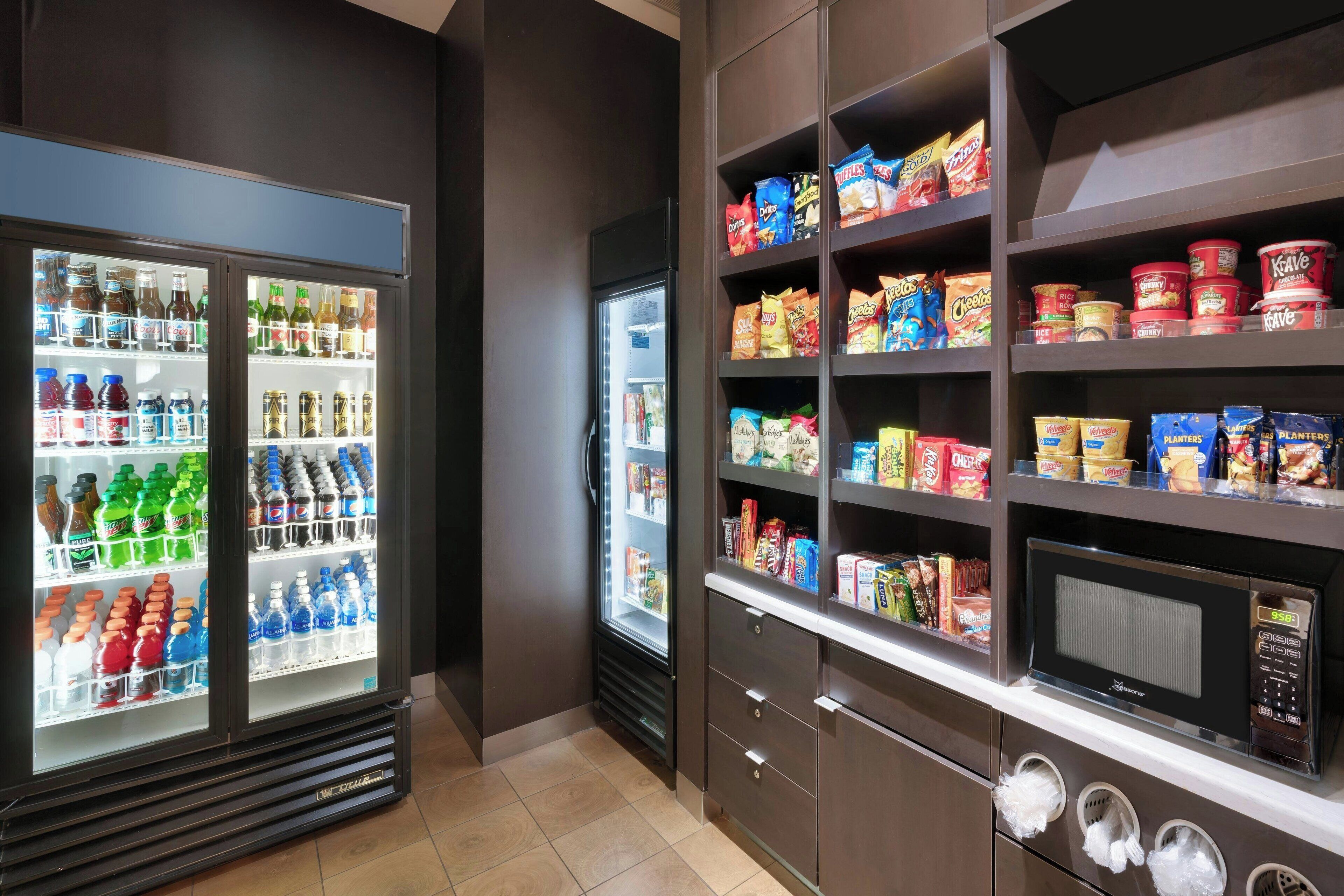 A kitchenette area with a refrigerator stocked with beverages and snacks, a microwave, and a small oven.