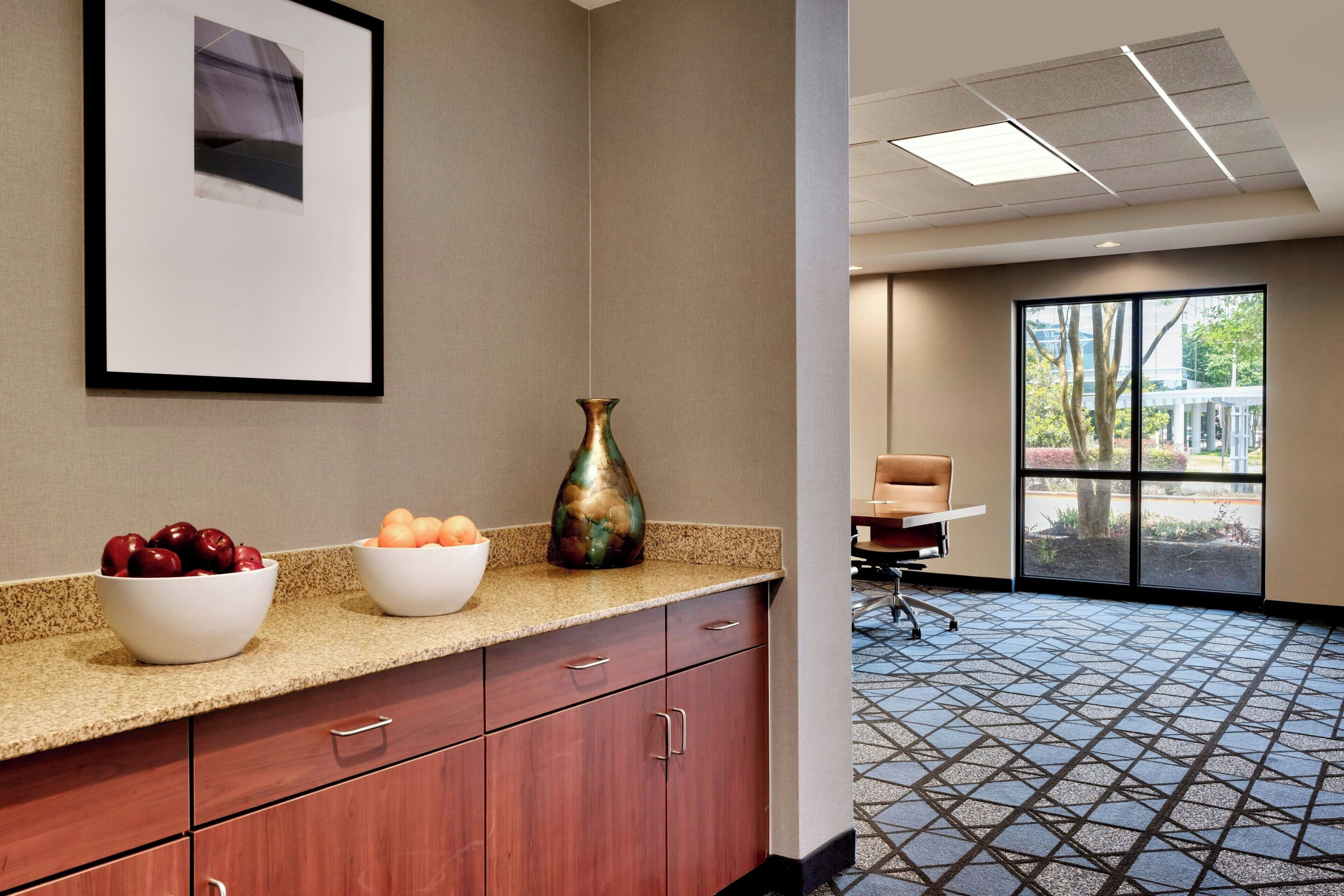 A hotel room with a kitchenette, a large window, and a patterned floor.