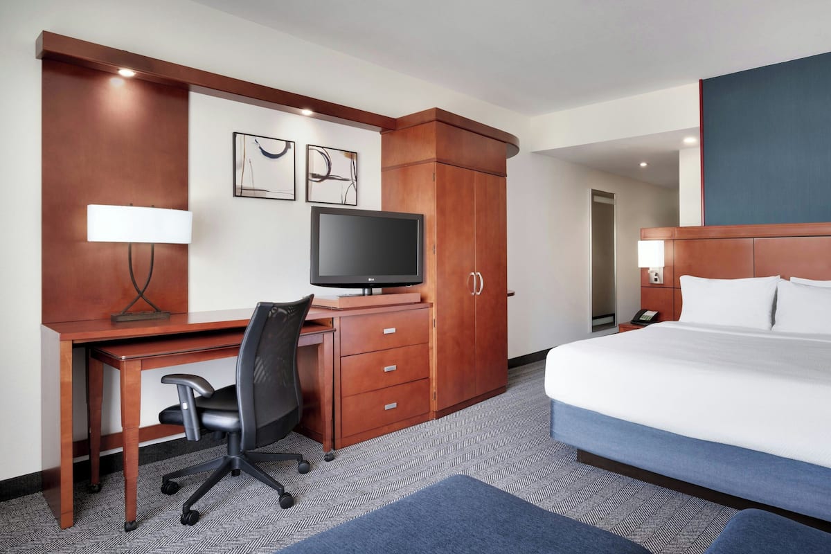 Une chambre d’hôtel équipée d’un lit, d’un bureau, d’une chaise, d’une télévision et d’une armoire.