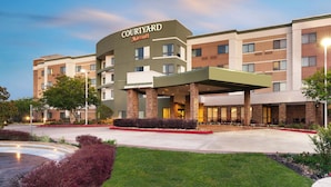 Ein Courtyard Marriott Hotel mit modernem Design, inklusive überdachter Eingangsbereiches und einer begrünten Innenhofanlage.