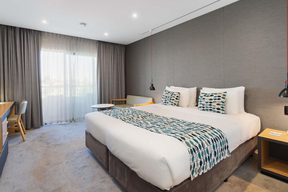 Una camera d'hotel moderna con un letto grande, una scrivania e una sedia.