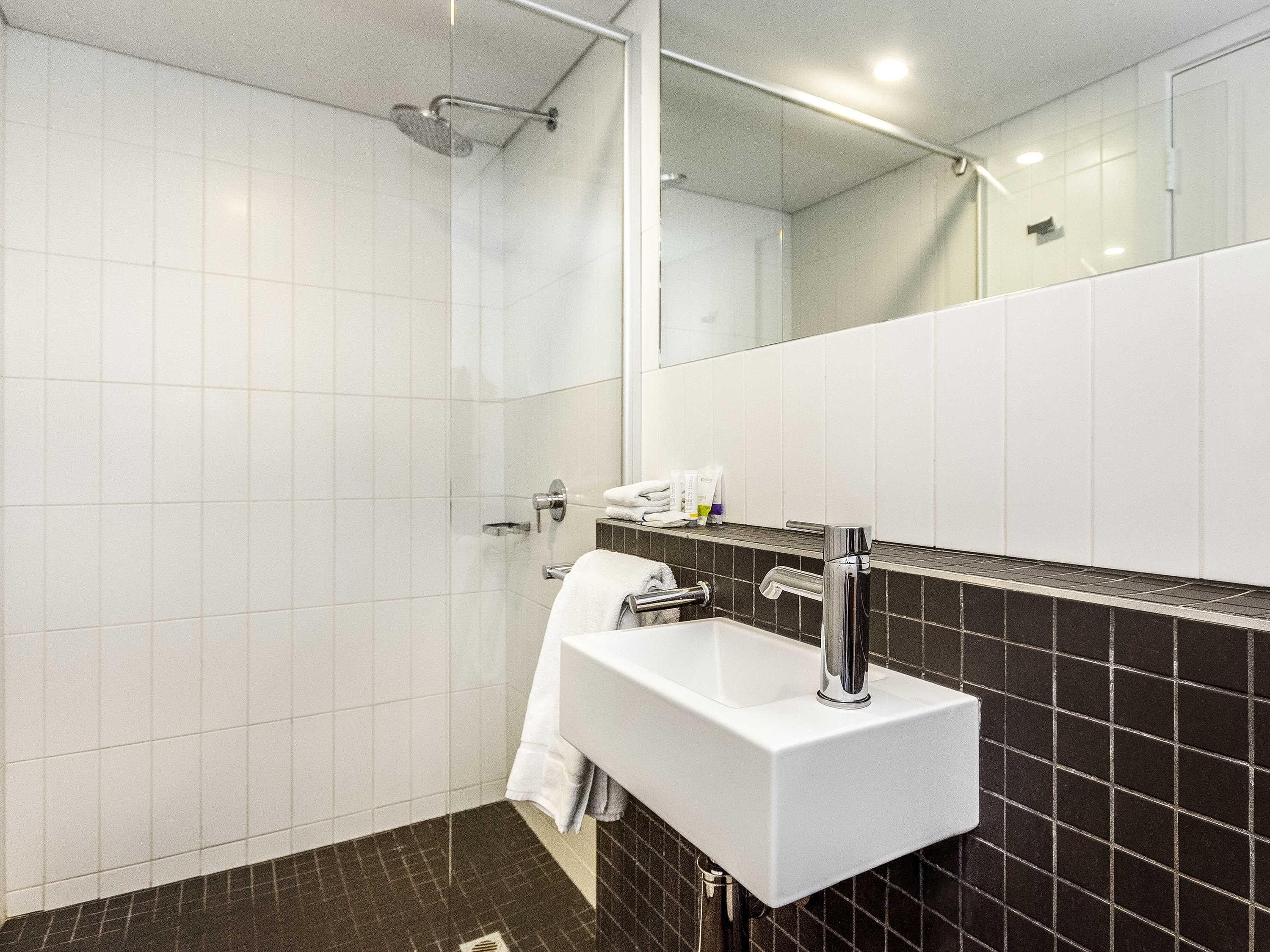A modern bathroom with a shower, a sink, and a mirror.