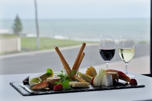 Una mesa con una tabla de embutidos, dos copas de vino y vista al océano.
