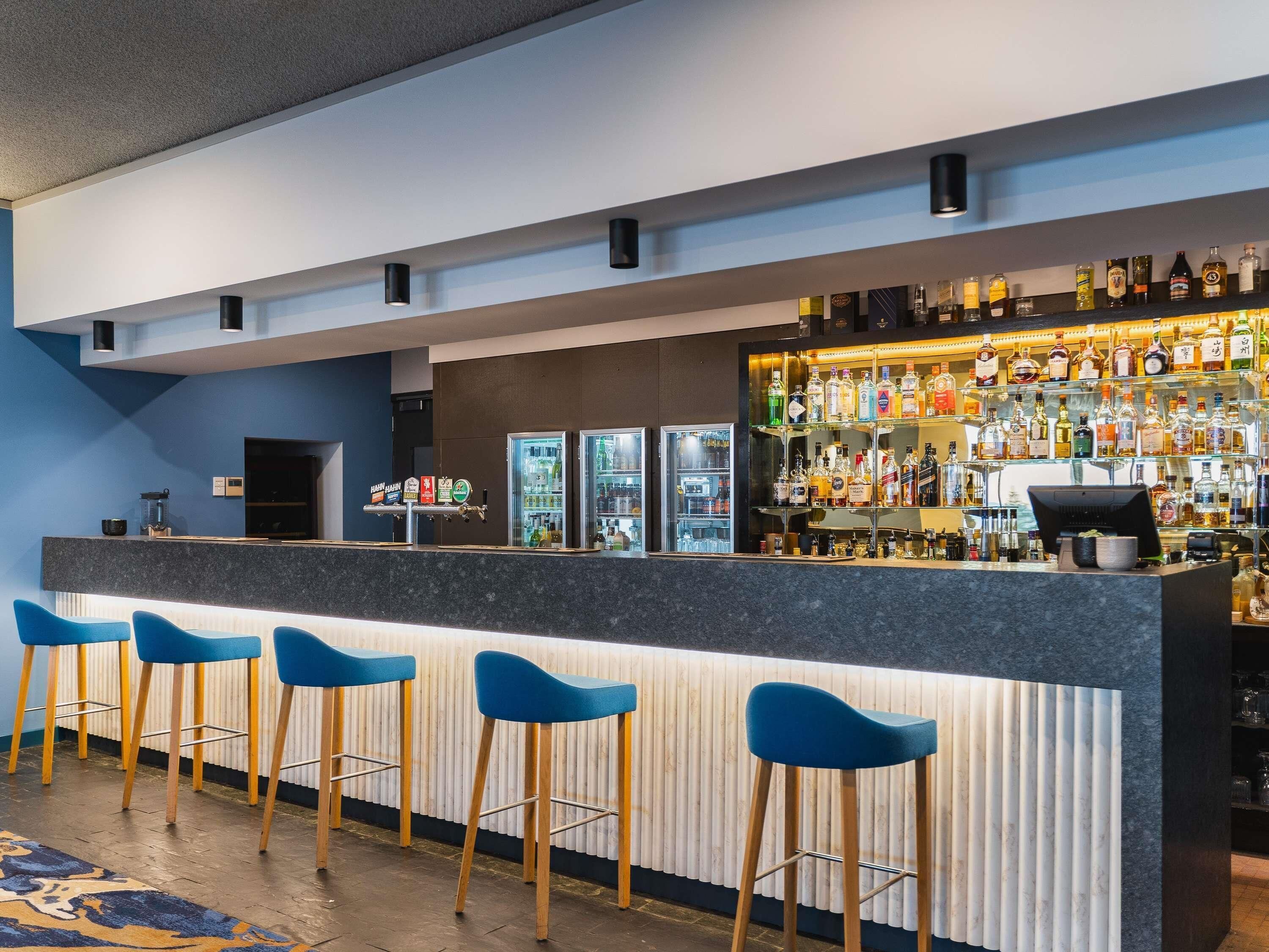 Un espace bar avec des tabourets, un comptoir et une variété de bouteilles d’alcool.