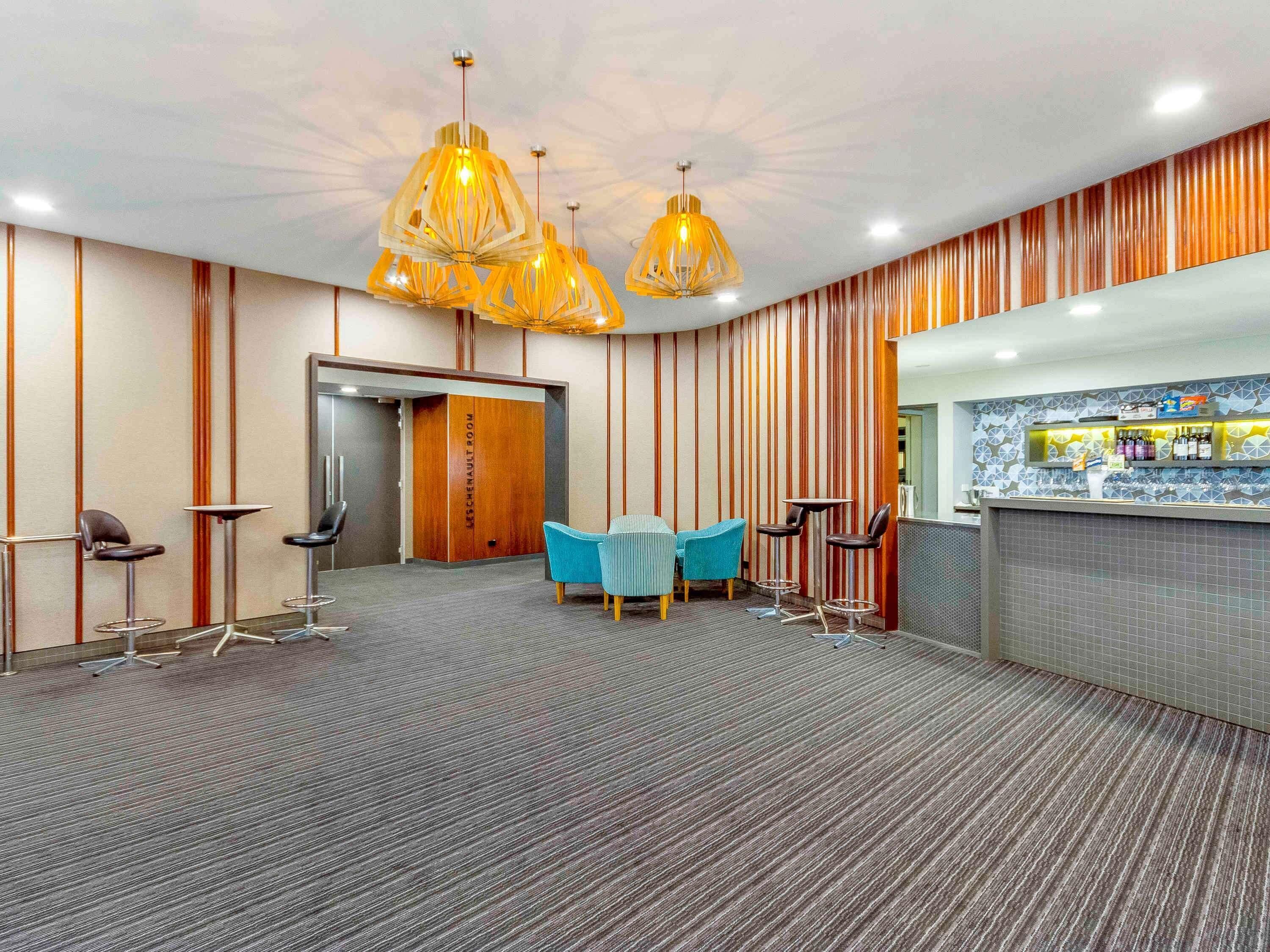 Un hall d’hôtel comprenant un comptoir d’accueil, un espace salon et une porte portant l’inscription « SALLE DES CHENNAUT ».