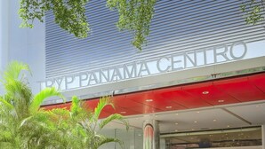 Exterior del edificio Panama Center con un toldo rojo, entrada de vidrio y palmeras al frente.