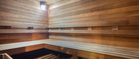 Una sauna con bancos de madera y un cubo de metal.