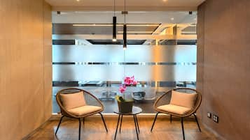 A modern interior with two wicker chairs, a small table with a potted orchid, and a view through a frosted glass partition.