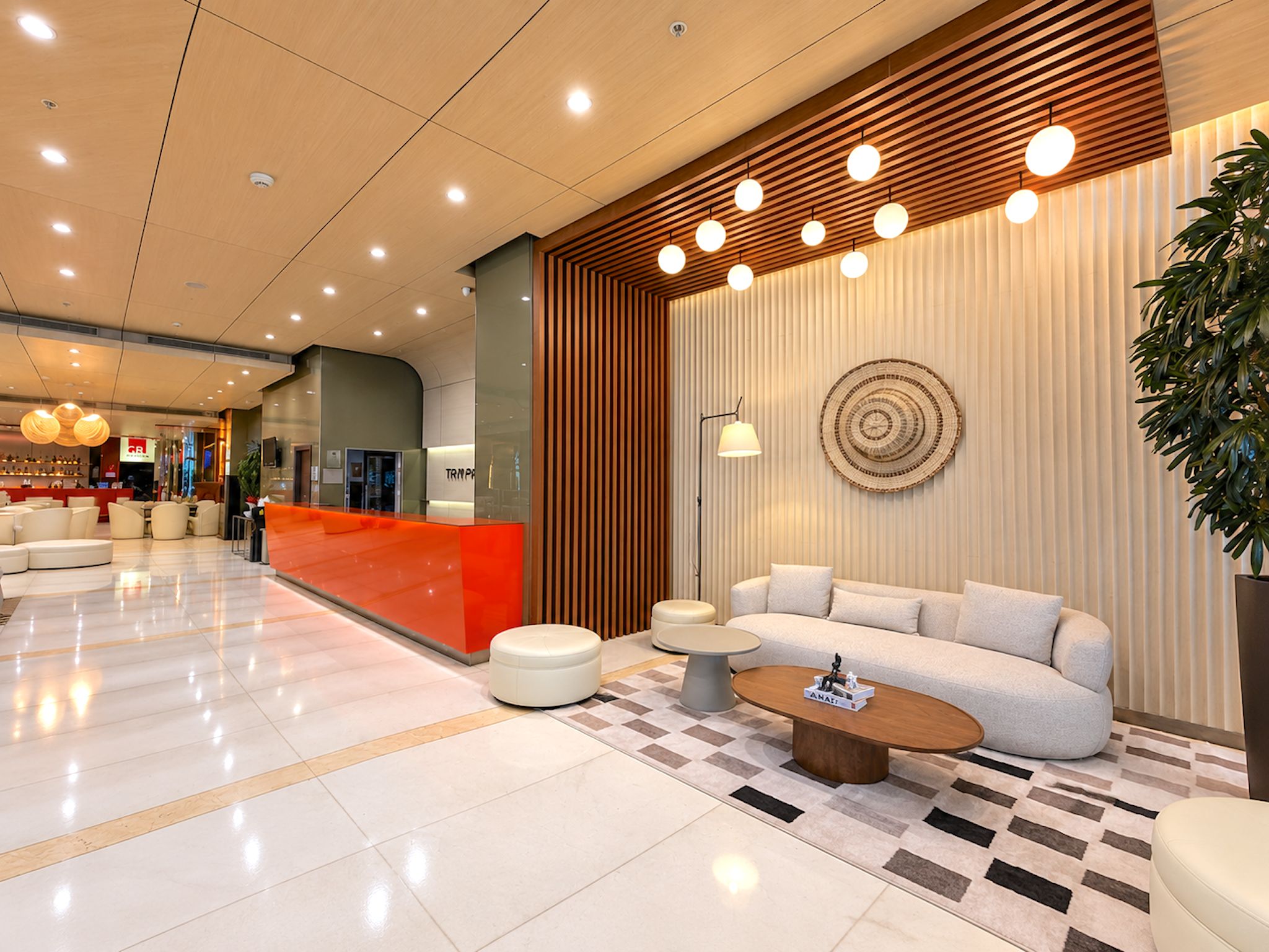 Un moderno vestíbulo de hotel con mostrador de recepción, zona de estar y una planta grande.