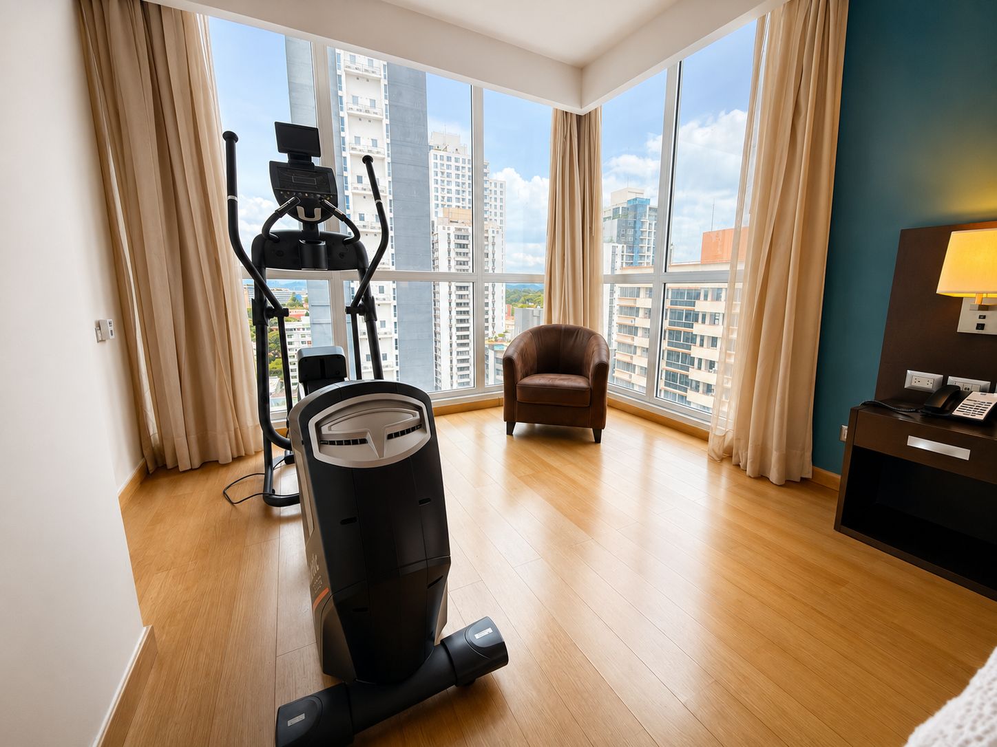 A hotel room with a treadmill, a massage chair, and a view of the cityscape.
