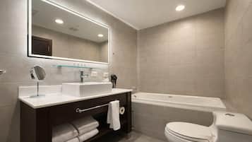 Un baño moderno con un espejo grande, una bañera y un inodoro.