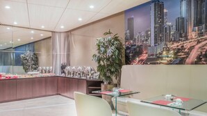 Un moderno vestíbulo de hotel con mostrador de recepción, zona de estar y un mural con vistas a la ciudad.