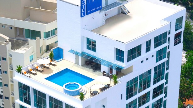 Un hotel con piscina en la azotea, mobiliario exterior y un cartel que dice "TRYP BY WYNHAM".
