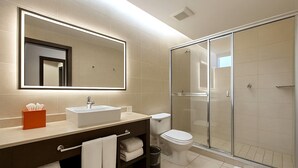 Un baño moderno con un espejo grande, un lavabo, un inodoro y una cabina de ducha de vidrio.