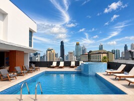 Una piscina al aire libre, sombrillas, sillones reclinables de piscina