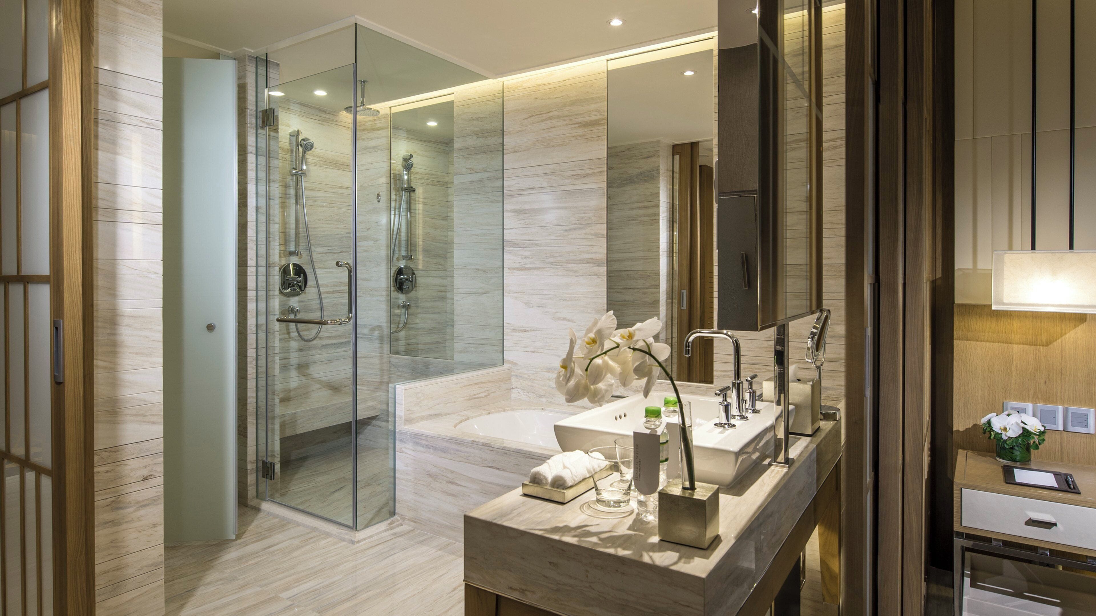 A modern bathroom with a glass-enclosed shower, a vanity with a mirror, and a sink.