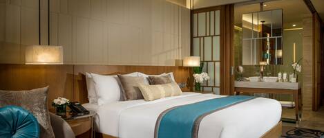 A hotel room with a large bed, bedside tables, a desk, a mirror, and a bathroom with a sink and mirror.